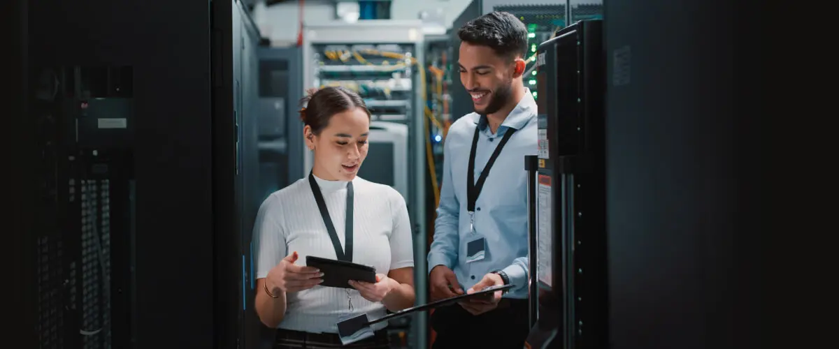 Male and female IT professionals comparing data on tablets inside a data center